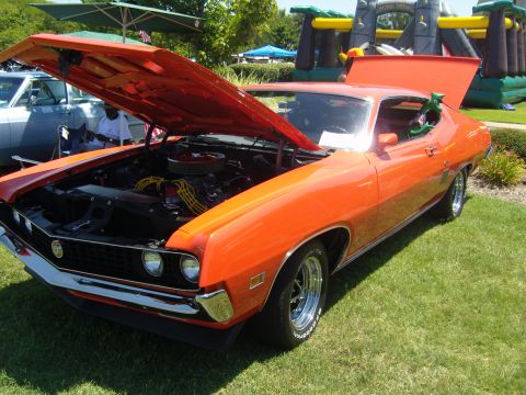 2007 Ford Mustang - A vintage orange car is displayed with its hood open, revealing the engine compartment.