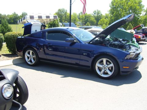 2007 Ford Mustang - Blue 2007 Ford Mustang GT at a car show, hood open.