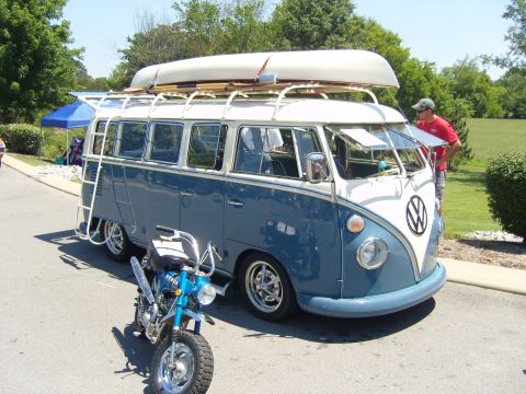 2007 Ford Mustang - A classic blue and white Volkswagen bus is parked outdoors with a canoe on its roof rack and a small blue motorcycle positioned in front of…