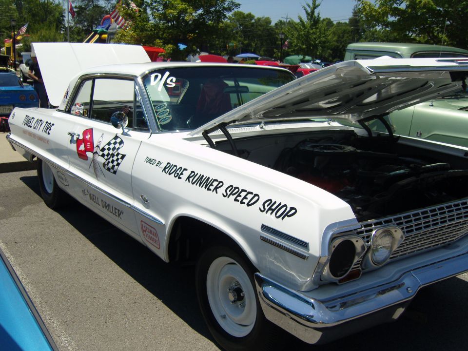 White 1963 coupe with hood open, "TUNED BY: RIDGE RUNNER SPEED SHOP" text on fender, checkered flag graphic