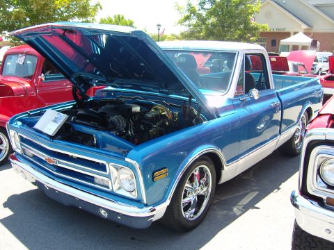 2007 Ford Mustang - A classic pickup truck with its hood open at an outdoor car show.