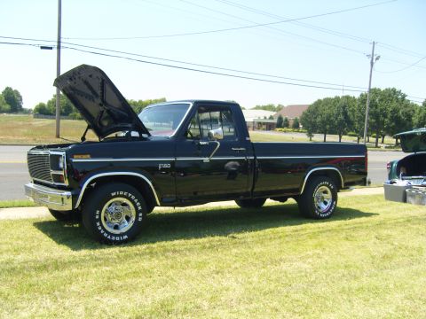 2007 Ford Mustang - A black Ford F-150 pickup truck is parked on grass with its hood open, with another vehicle partially visible to the right.