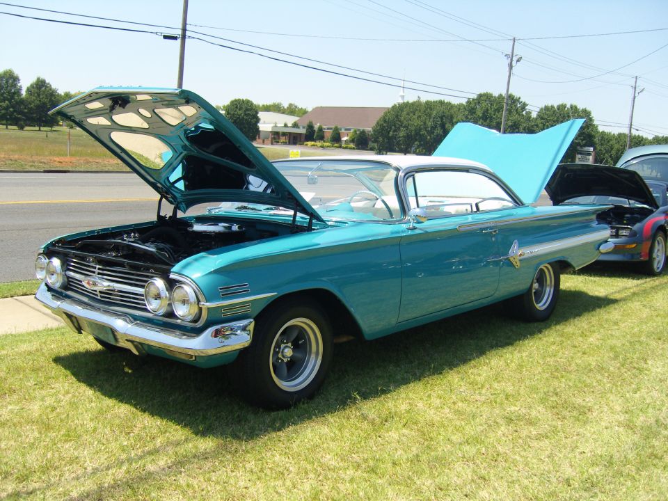 Teal 1960 Chevrolet Impala with hood open, parked on grass next to another car