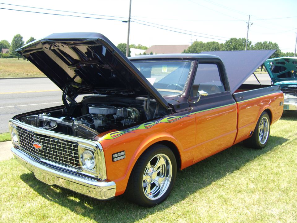 Orange and black pickup truck with flames, hood and bed open, chrome wheels