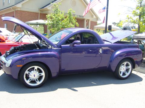 2007 Ford Mustang - A purple Chevrolet SSR pickup truck is displayed with its hood and trunk open at an outdoor car show.