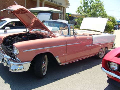2007 Ford Mustang - A classic pink convertible is displayed with its hood and trunk open, parked next to another vehicle.