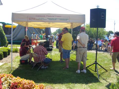 2007 Ford Mustang - An outdoor event features a tent with sponsors' logos, people mingling, and an inflatable attraction.