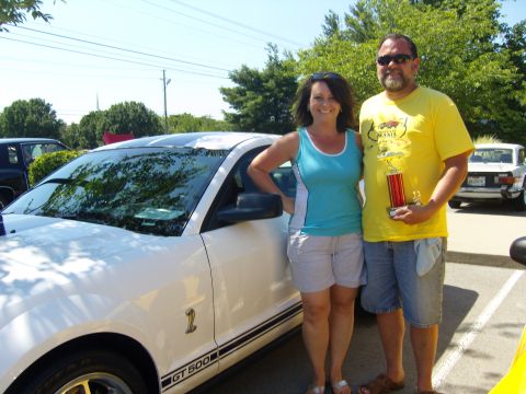 2007 Ford Mustang - Couple poses with their trophy beside a white 2007 Ford Mustang GT500 at an outdoor event.