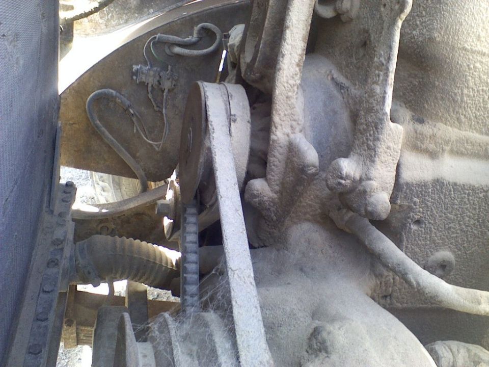 Close-up of a dusty engine belt and pulley system with visible cobwebs
