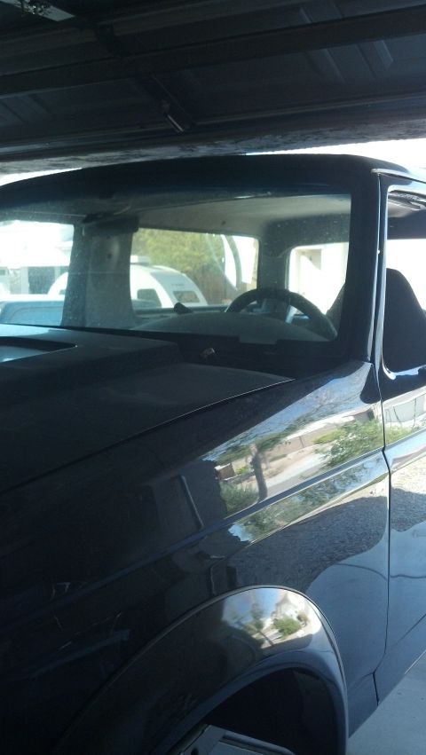 1995 Ford Bronco - The front corner of a dark SUV is visible, parked indoors with another vehicle in the background.