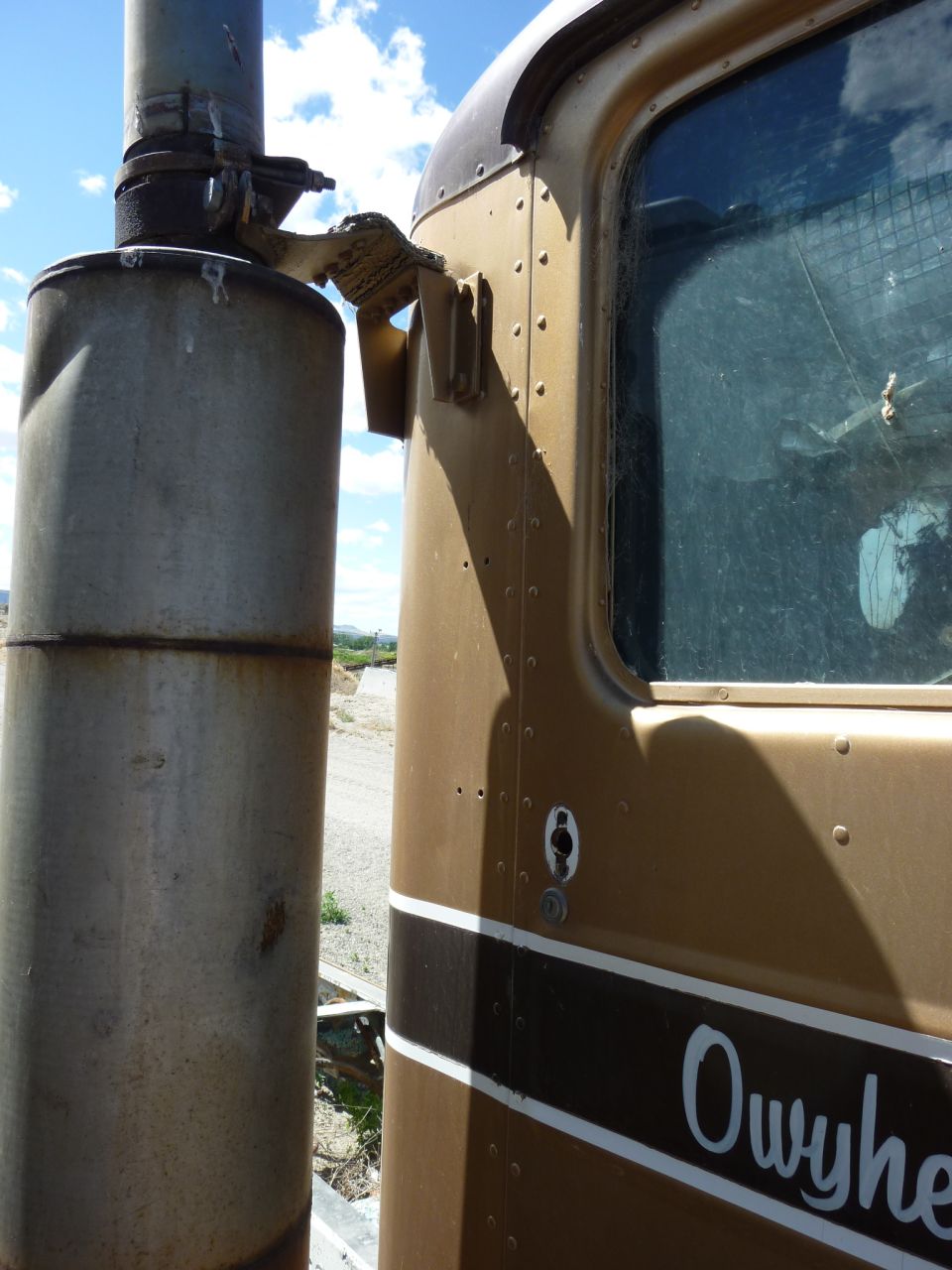 Brown truck cab side with a large vertical exhaust stack next to it. "Owyhee" is written on the door