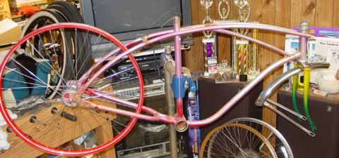1953 Ford Mainline - A bicycle frame and wheels are shown in a room with trophies and electronics in the background.