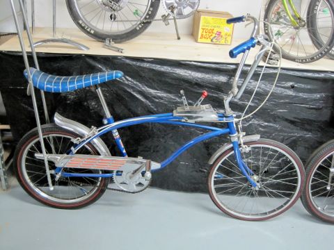 1953 Ford Mainline - A blue bicycle with a distinctive banana seat and sissy bar is shown, with another bicycle partially visible.