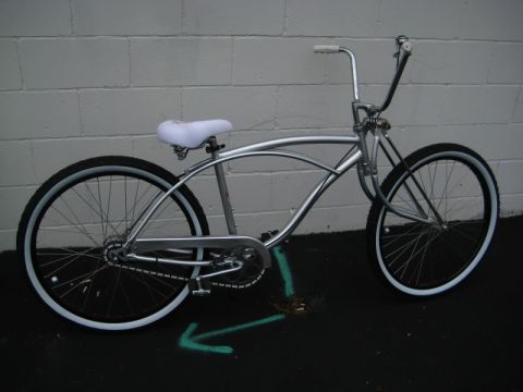 1953 Ford Mainline - A silver bicycle with a distinctive frame design and whitewall tires is shown from the side.