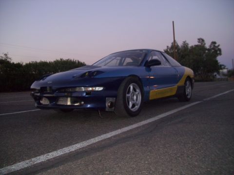 1995 Ford Probe - A modified Ford Probe sits on a road at dusk, its two-tone paint scheme visible.