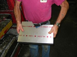 1993 Ford Taurus - A man holds a metal plate with red text and numbers, possibly a part or label.