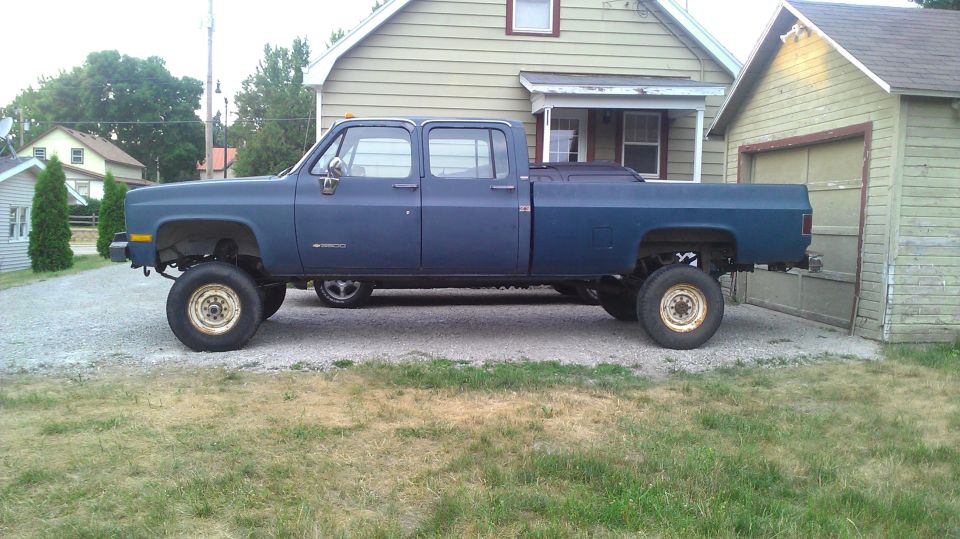 Blue 1980s Chevrolet crew cab dually pickup parked in residential yard