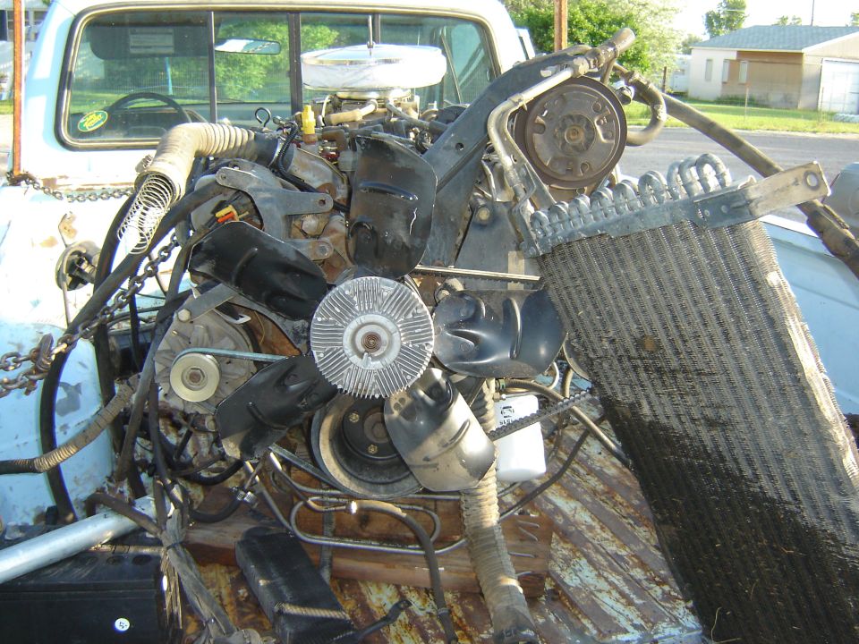 Engine and radiator assembly with fan and belts, partially installed in a truck bed