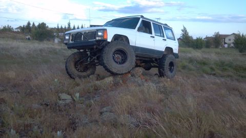 1995 Jeep Cherokee - This modified 1995 Jeep Cherokee is shown navigating a rocky incline under a cloudy sky.