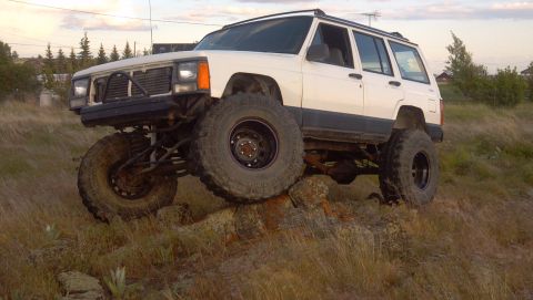1995 Jeep Cherokee - A modified 1995 Jeep Cherokee navigates a rocky incline with its large tires.
