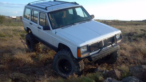 1995 Jeep Cherokee - This Jeep Cherokee is shown navigating a rough, grassy landscape with large tires.