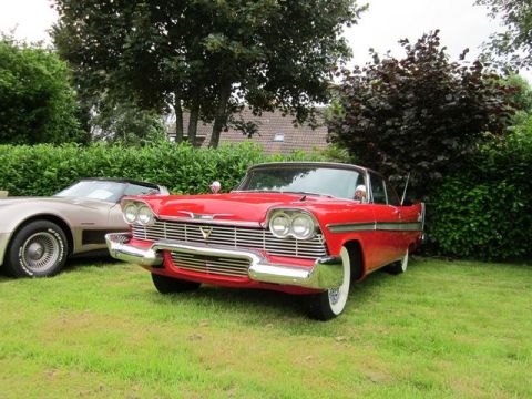 1991 Ford LTD Crown Victoria - A red 1957 Plymouth Belvedere 2-door hardtop is parked on a grassy lawn next to another vehicle.