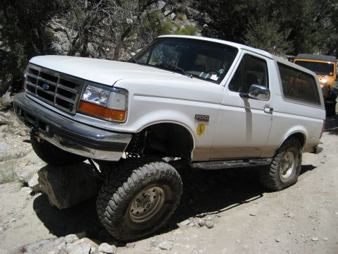 1996 Ford Bronco - This 1996 Ford Bronco navigates a challenging off-road path, demonstrating its capability on rough terrain.