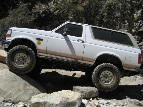 1996 Ford Bronco - A white 1996 Ford Bronco navigates a challenging rocky trail, its off-road capabilities.