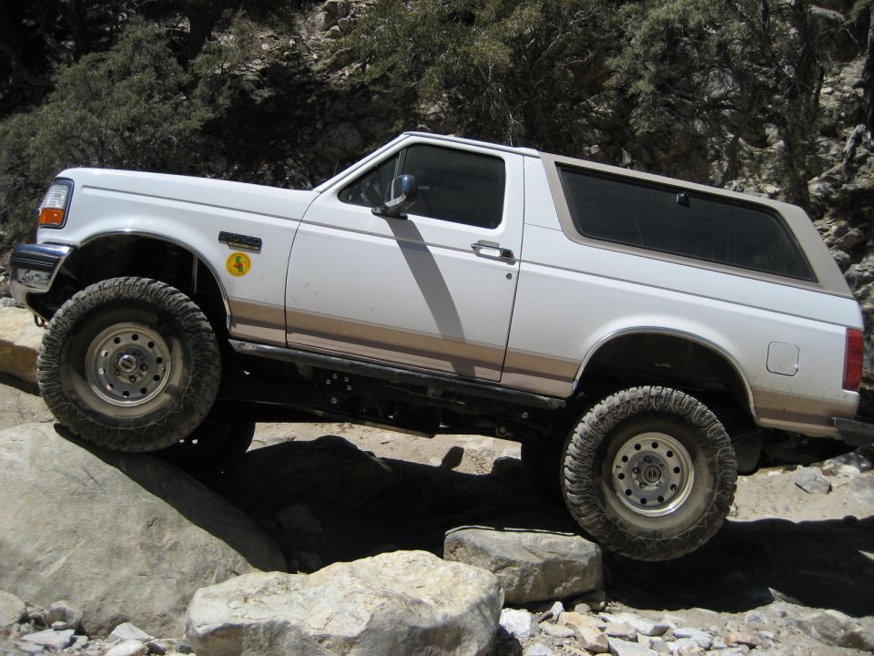 White 1996 Ford Bronco side view on rocky terrain