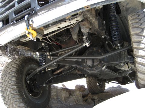 1996 Ford Bronco - The undercarriage of a modified off-road vehicle is shown, highlighting its robust suspension and drivetrain components.