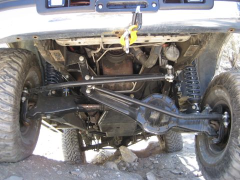 1996 Ford Bronco - The underside of a modified off-road vehicle is shown, highlighting its heavy-duty suspension and drivetrain components.