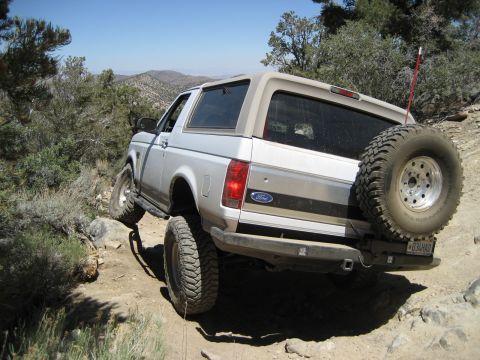 1996 Ford Bronco - A silver Ford Bronco navigates a challenging rocky terrain on a sunny day.