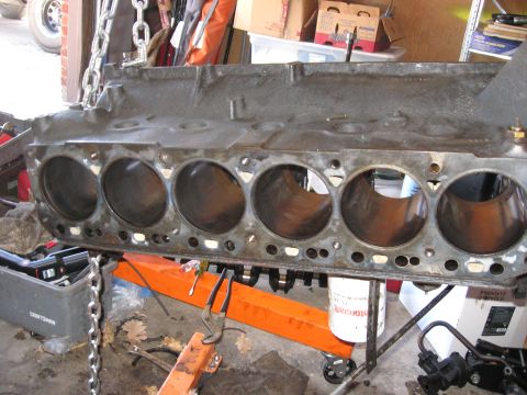 1981 Ford Bronco - Engine block suspended by chains and resting on an engine stand, ready for rebuild.