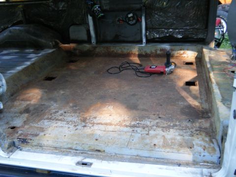 1988 Ford E350 - The interior of a van shows a rusted floor and insulation, with tools present.