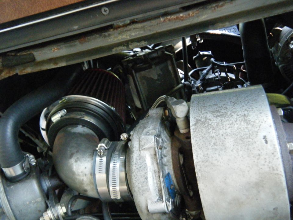 Engine bay with turbocharger, air intake, and hoses visible