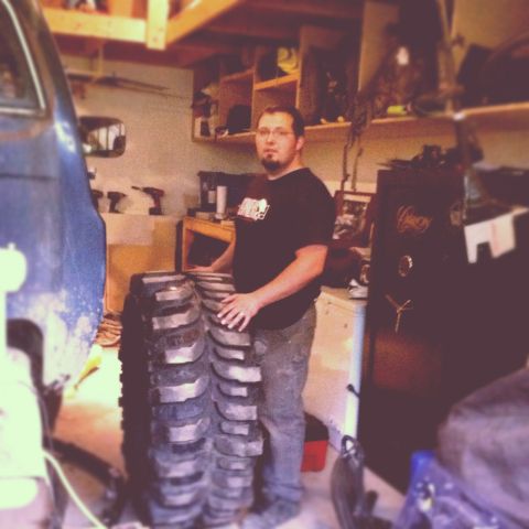 1983 Chevrolet C/K Pickup - Man with large tires in a workshop setting.