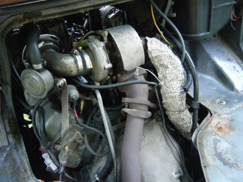 1988 Ford E350 - The engine bay shows a turbocharger and exhaust system, with visible rust on the vehicle's body.