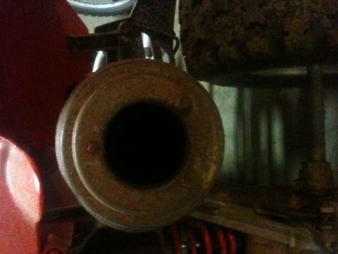 1990 Chevrolet Suburban - A close-up view of a rusty exhaust pipe, showing its circular opening and surrounding metal components.
