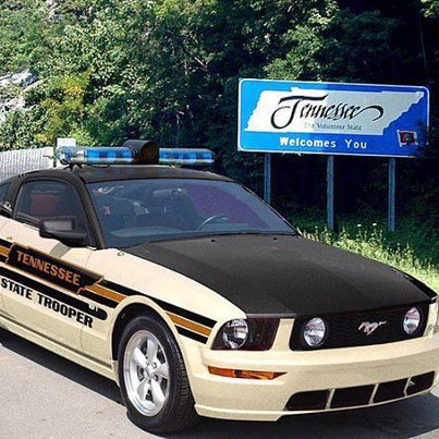 2007 Ford Mustang - Tennessee State Trooper car parked near a welcome sign for the state.