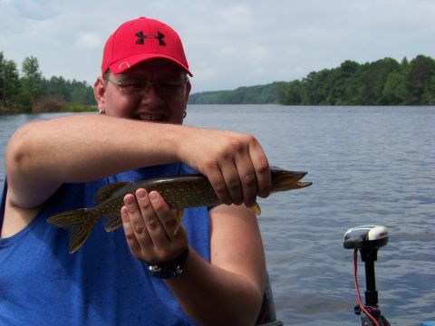 1996 Ford F-150 - A man proudly displays a freshly caught fish while on a boat on a lake.