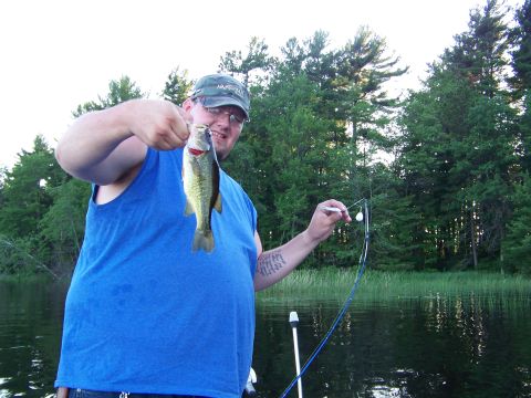 1996 Ford F-150 - A fisherman proudly displays his catch while out on the water, surrounded by trees.