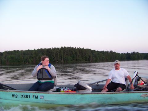 1996 Ford F-150 - Two people enjoy a boat ride on a calm lake with a wooded shoreline.