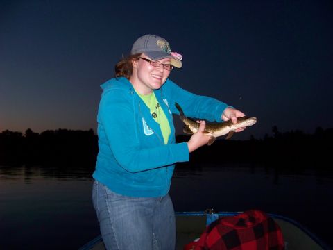 1996 Ford F-150 - A woman proudly displays a freshly caught fish while on a boat during twilight.