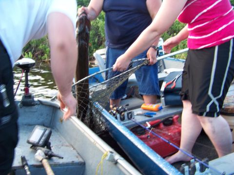 1996 Ford F-150 - Three people are in a boat, one holding a large fish while another uses a net.