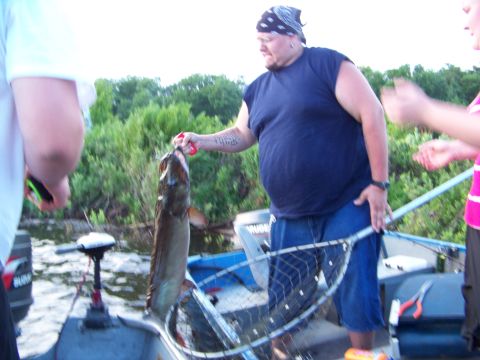 1996 Ford F-150 - A man proudly displays a large fish he caught while on a boat with others.
