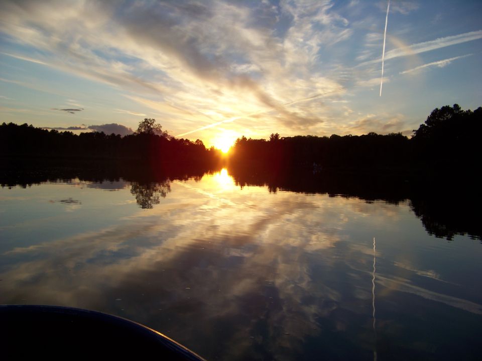 sunset over a lake with clouds reflecting on the water