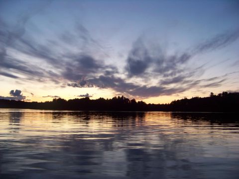 1996 Ford F-150 - A tranquil lake reflects the colors of a sunset, with dark trees lining the horizon.