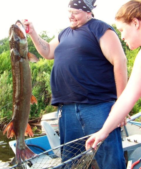 1996 Ford F-150 - Two people are on a boat, one holding up a large fish they just caught.