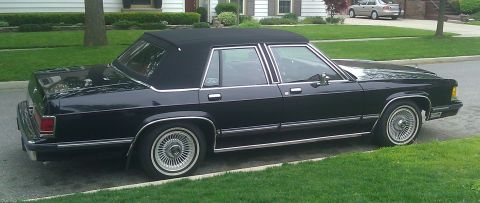 1991 Mercury Grand Marquis - A black 1991 Mercury Grand Marquis sedan with a vinyl top is parked on a residential street.