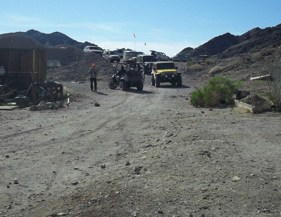 Yellow Jeep and other off-road vehicles parked on a dirt road in a desert